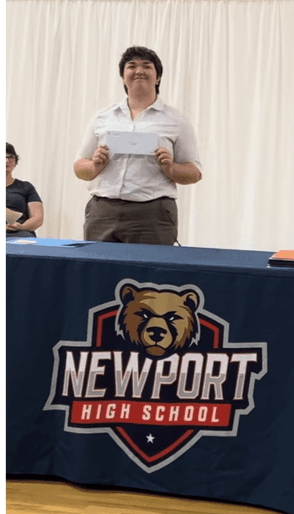 Student standing and smiling with their scholarship award in hand. 